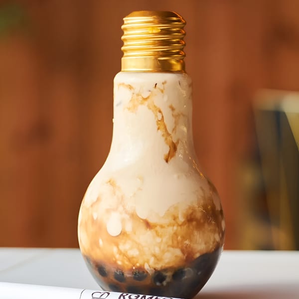 Romeo Tea's "My Cup of Love" boba drink in a lightbulb-shaped bottle with a gold cap.