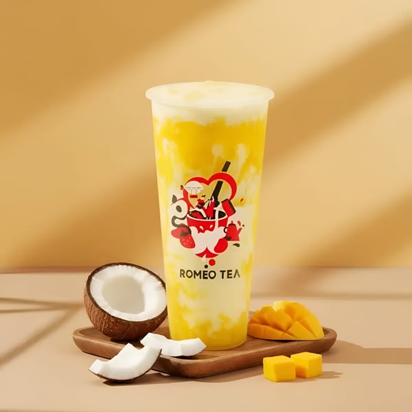 Romeo Tea mango and coconut drink with mango slices and coconut pieces on a wooden tray.